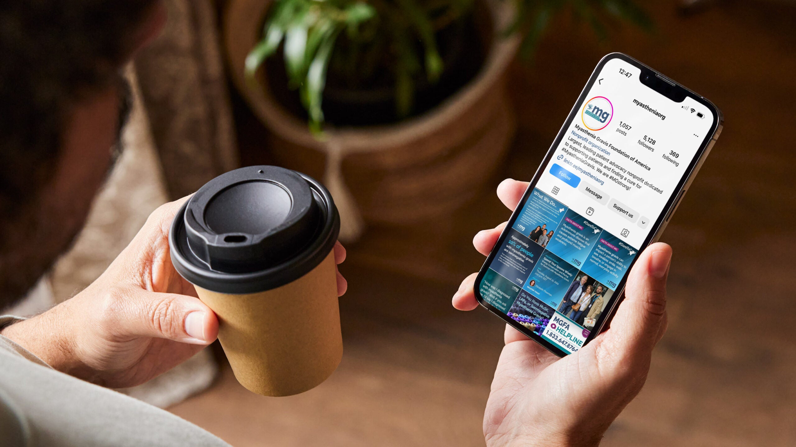 A person holds a coffee cup in their left hand and a phone with the MGFA Instagram page pulled up in their right hand.